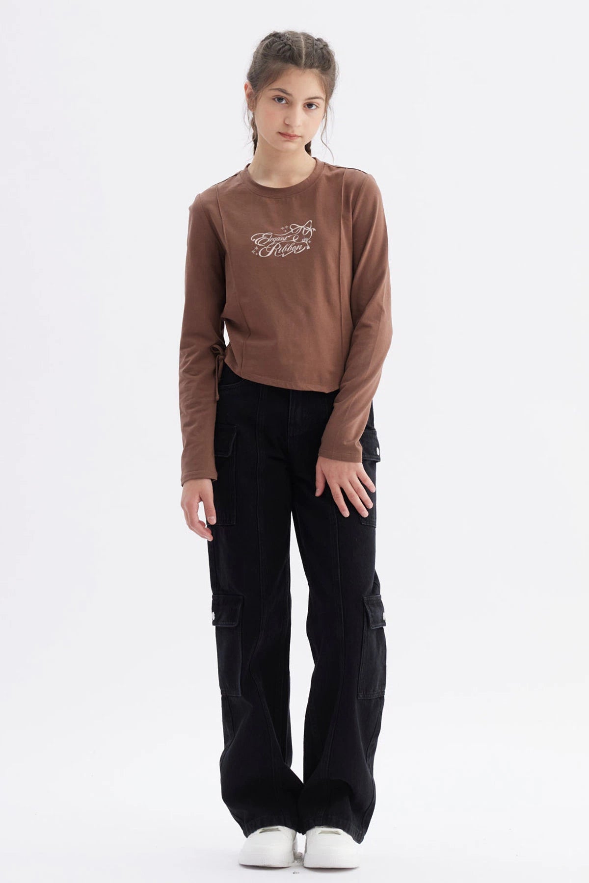 Polera niña slim café con diseño frontal de texto 'Elegant Ribbon' en estilo cursivo centrado sobre el pecho