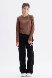 Polera niña slim café con diseño frontal de texto 'Elegant Ribbon' en estilo cursivo centrado sobre el pecho
