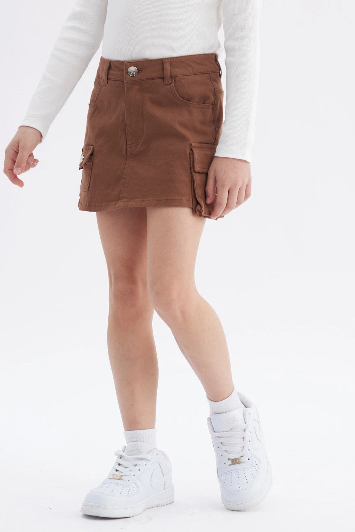 Falda corta café para niña con bolsillos grandes al frente prenda lisa diseño casual sin estampas