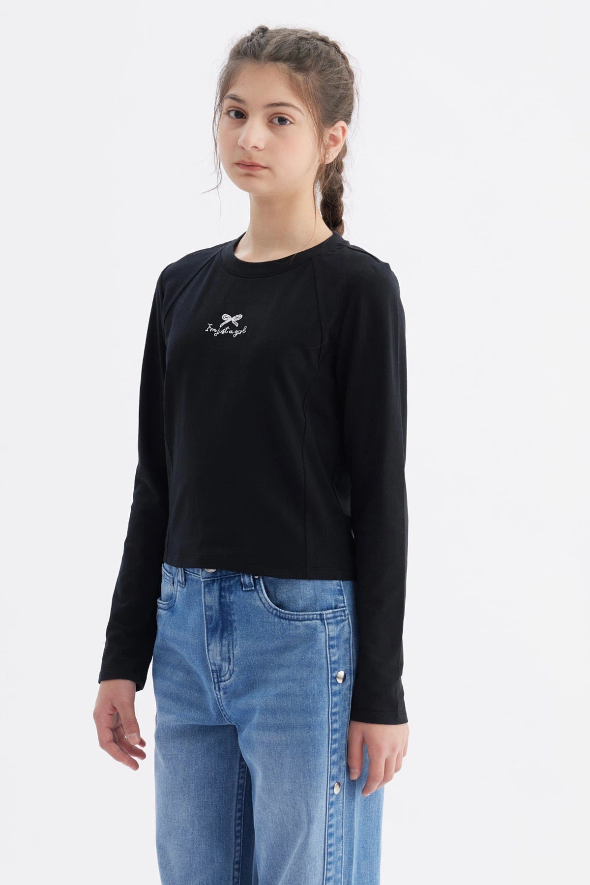 Polera negra de manga larga para niña con estampa de moño y texto I'm just a girl en el centro del pecho