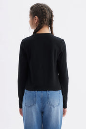 Polera negra de manga larga para niña con estampa de moño y texto I'm just a girl en el centro del pecho