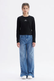 Polera negra de manga larga para niña con estampa de moño y texto I'm just a girl en el centro del pecho