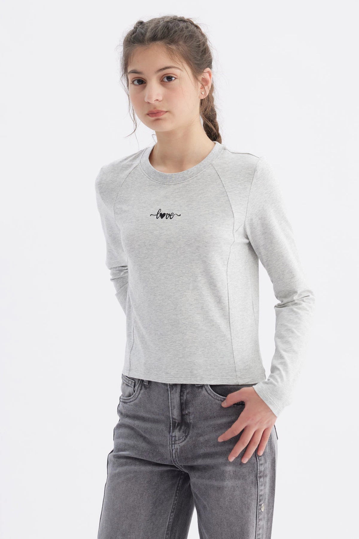 Polera gris melange para niña con costuras visibles y la palabra love en el pecho en letra cursiva negra