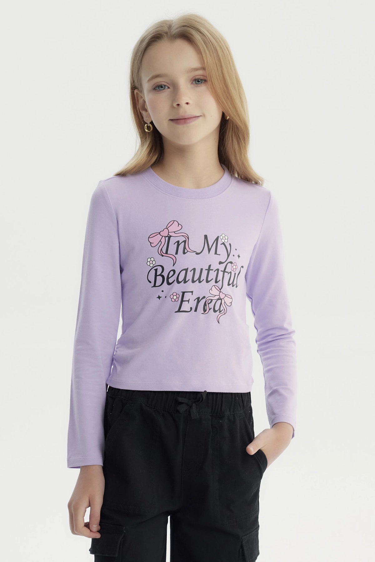 Polera slim lila para niña con estampa frontal de texto In My Beautiful Era y lazos rosados diseño floral