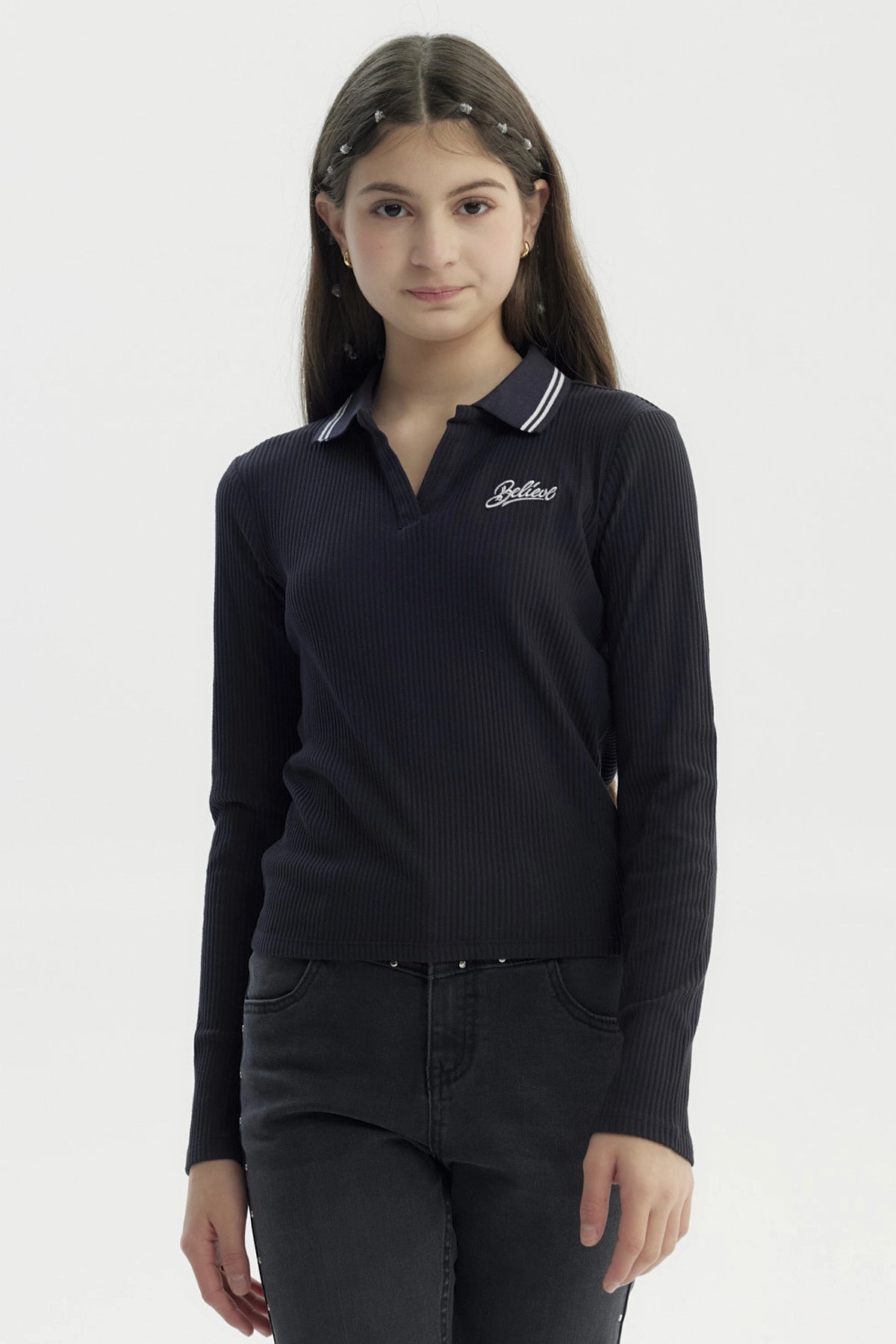 Polera negra de manga larga para niña con escote en V y texto Believe bordado en el pecho izquierdo