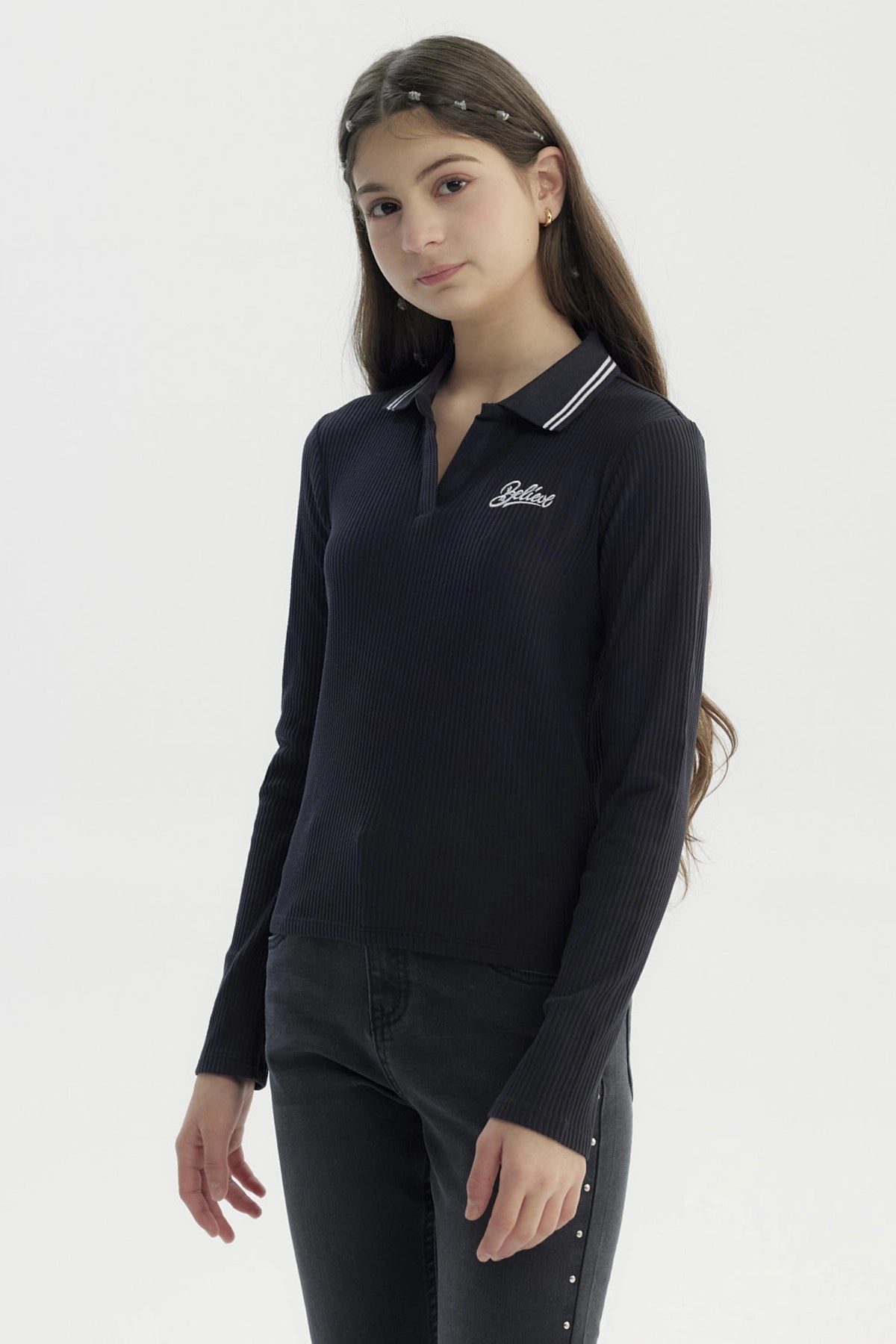 Polera negra de manga larga para niña con escote en V y texto Believe bordado en el pecho izquierdo