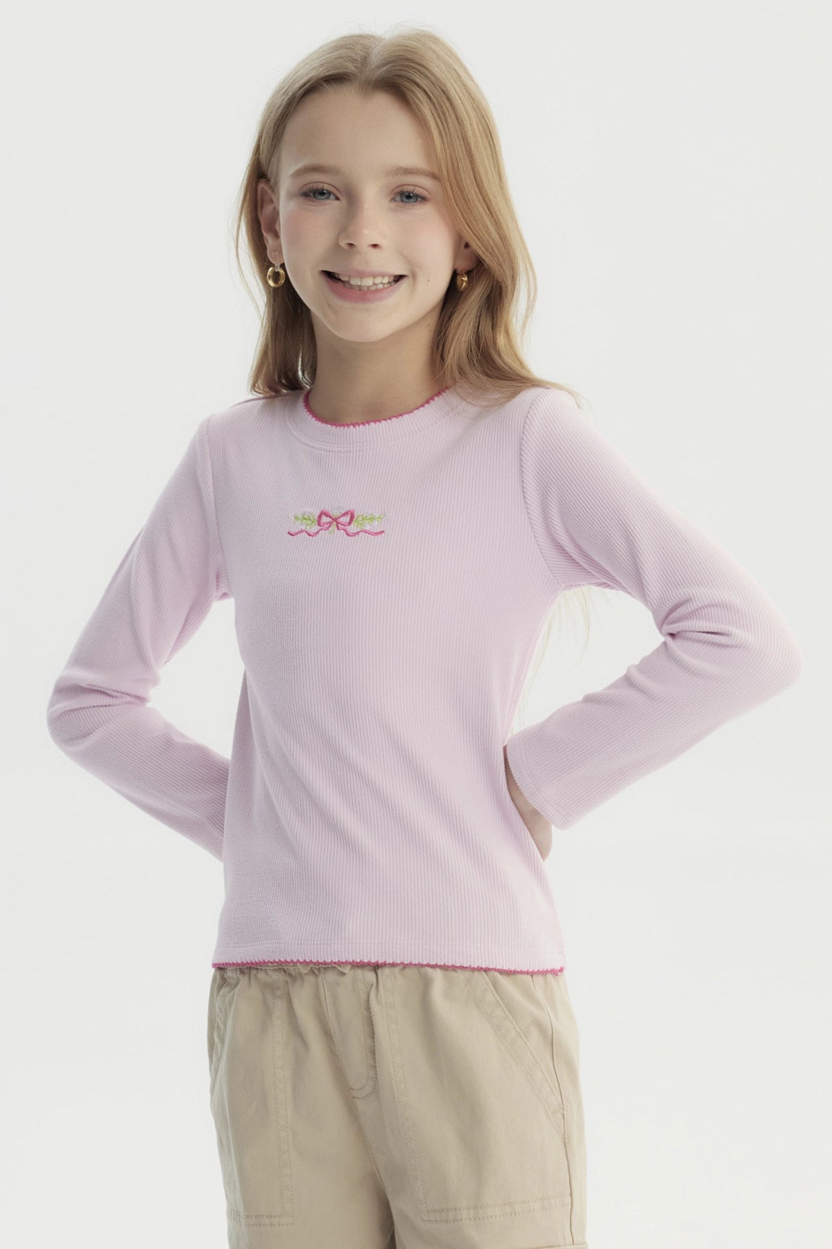 Polera slim rosada para niña con lazo bordado pequeño en el pecho estilo minimalista manga larga