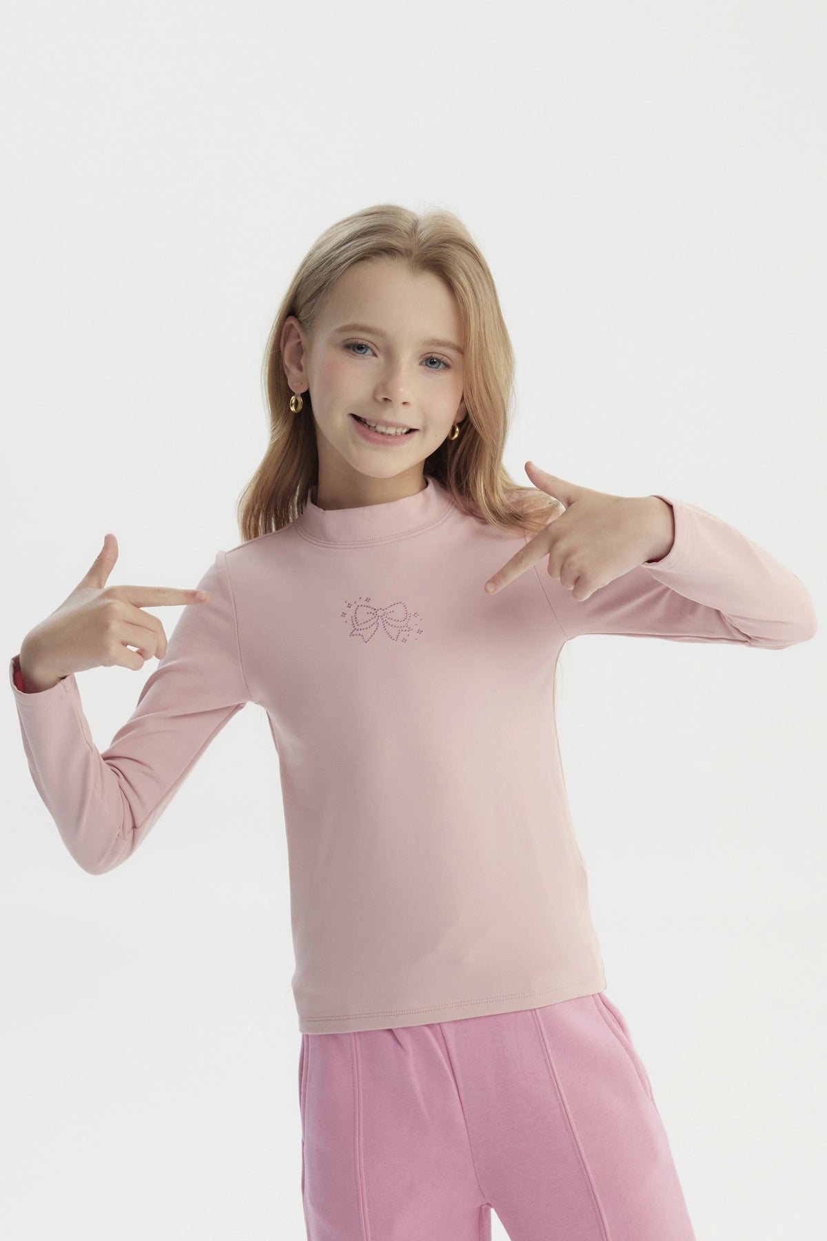 Polera slim rosada para niña con diseño de lazo en el pecho estilo minimalista y sin estampa adicional