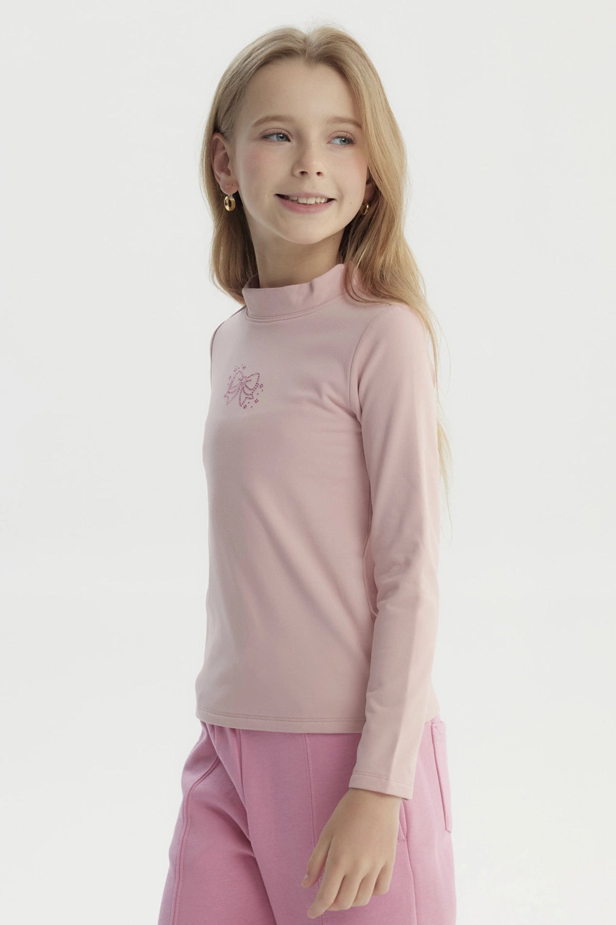Polera slim rosada para niña con diseño de lazo en el pecho estilo minimalista y sin estampa adicional