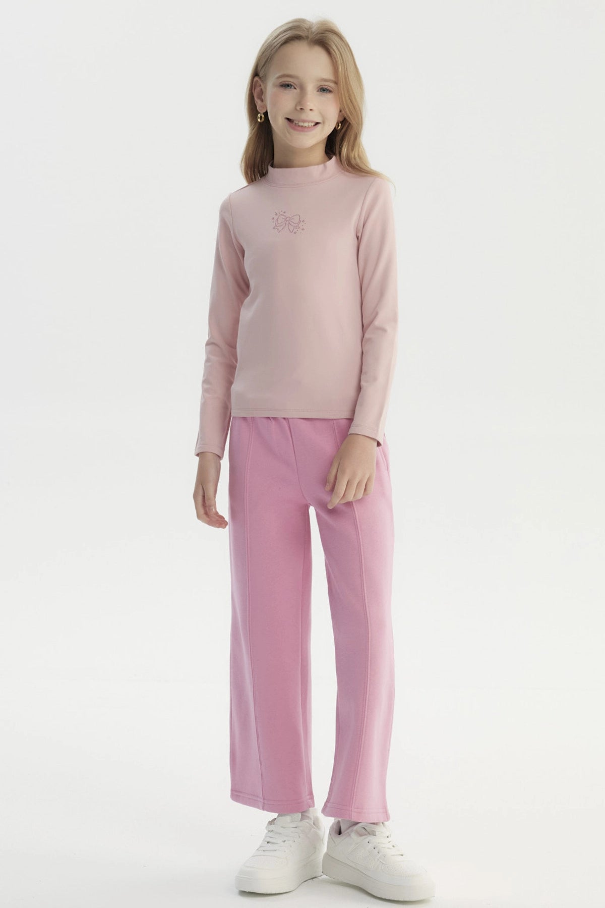 Polera slim rosada para niña con diseño de lazo en el pecho estilo minimalista y sin estampa adicional