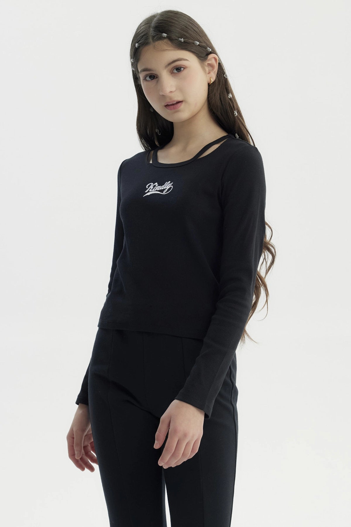 Polera ajustada negra para niña con texto 'Kindly' en el pecho en estilo cursivo pequeña estampa blanca sin más detalles