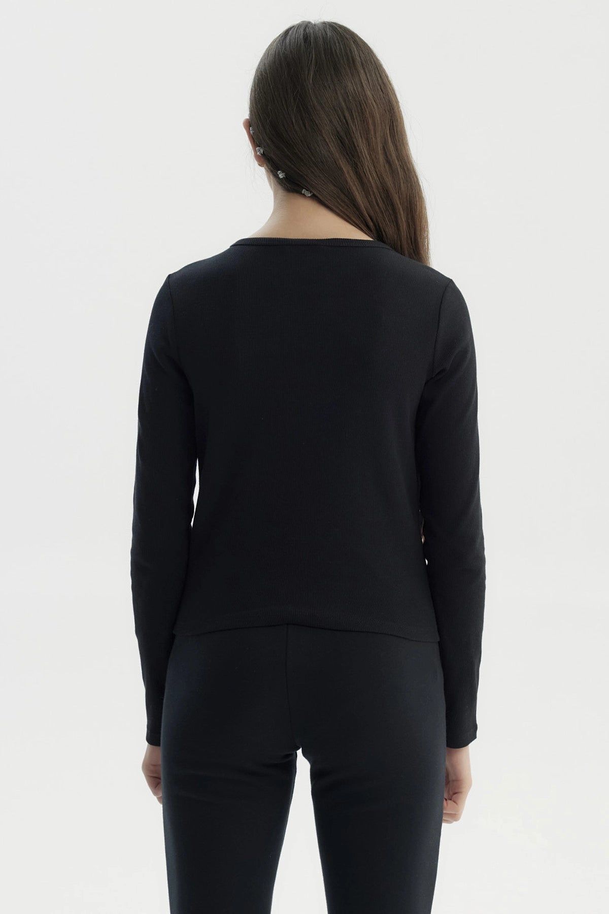 Polera ajustada negra para niña con texto 'Kindly' en el pecho en estilo cursivo pequeña estampa blanca sin más detalles