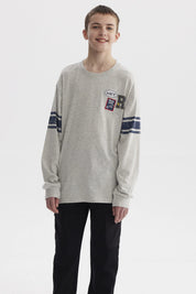 Polera gris melange de niño con franjas azules en mangas y parches tipo college en el pecho estilo casual urbano