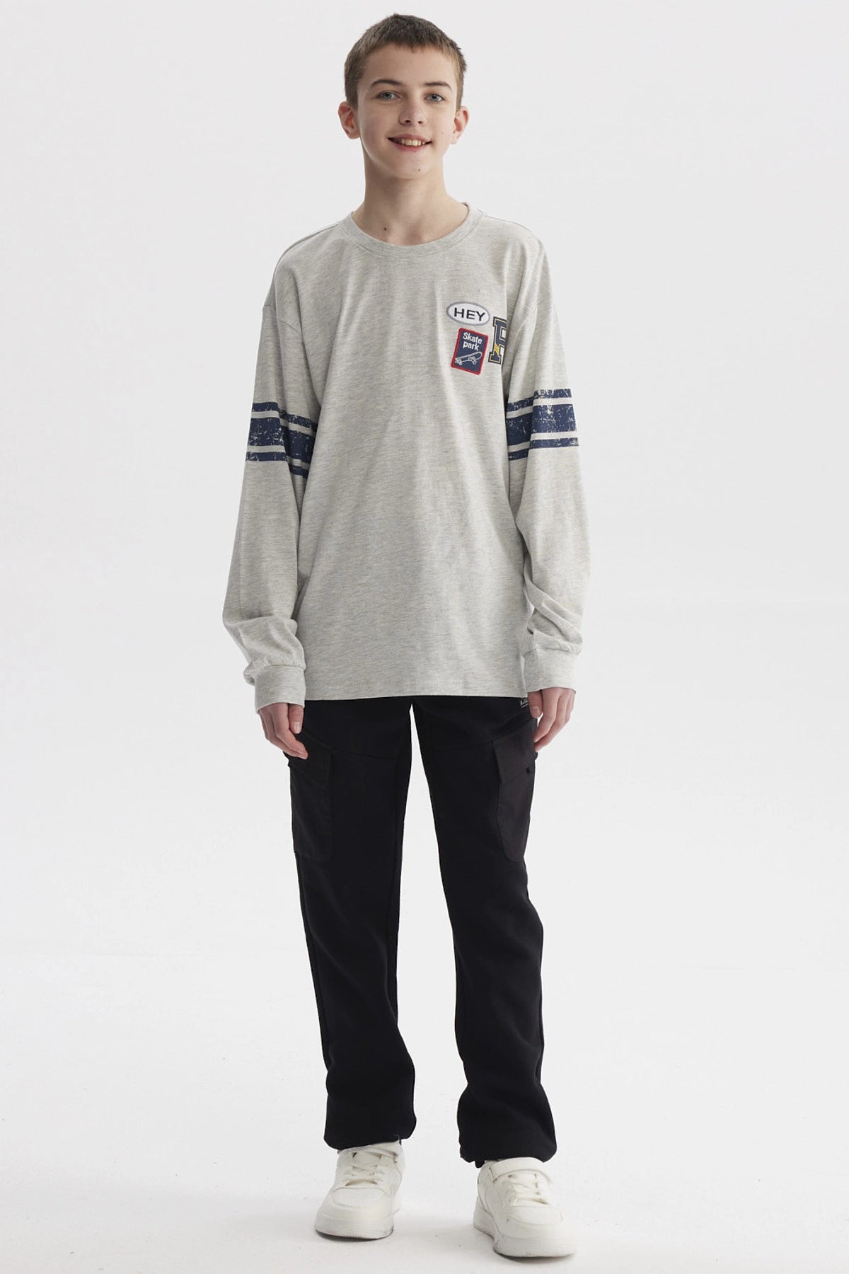 Polera gris melange de niño con franjas azules en mangas y parches tipo college en el pecho estilo casual urbano
