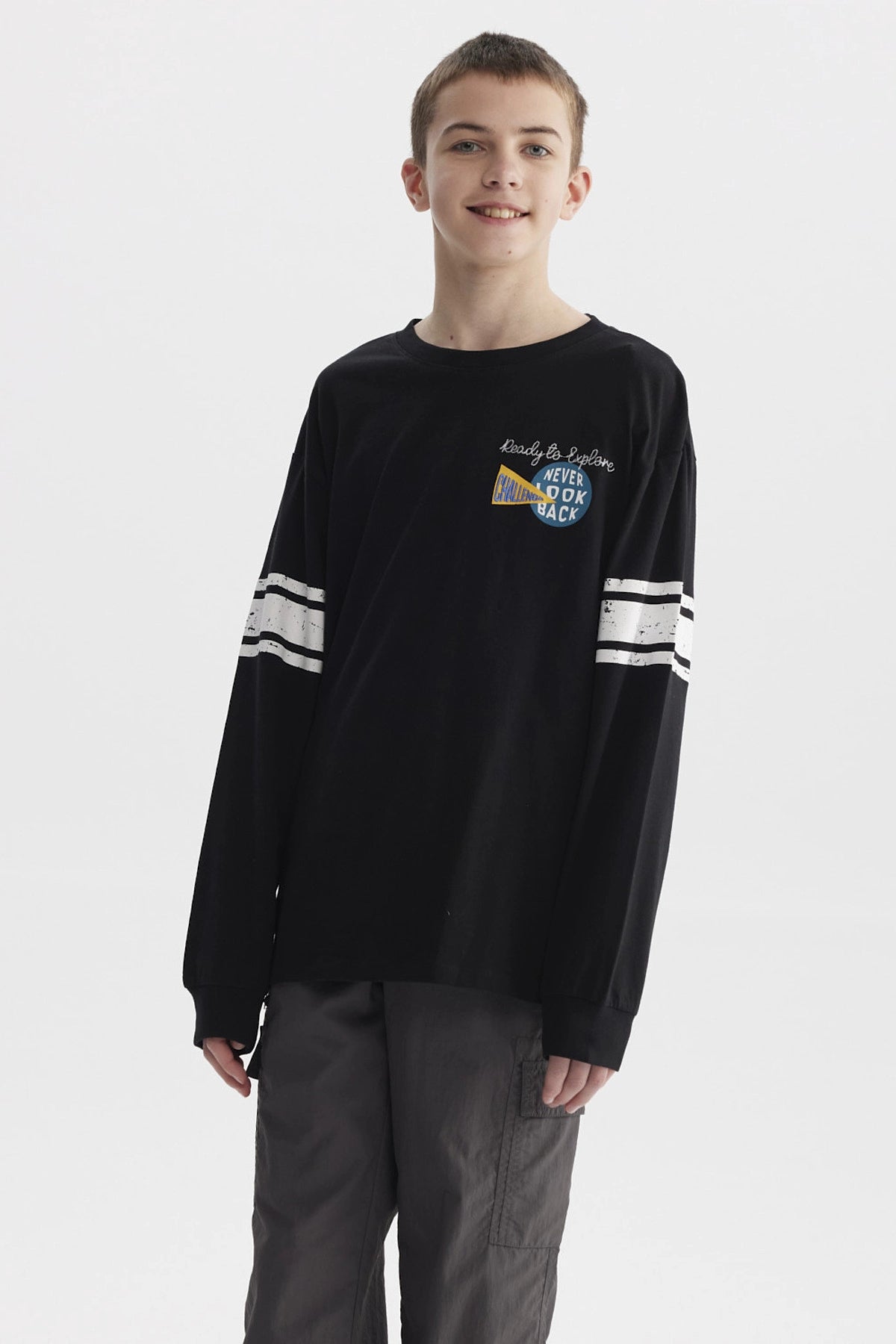 Polera negra de niño con franjas blancas en mangas y estampa colorida de texto 'Never Look Back' en el pecho
