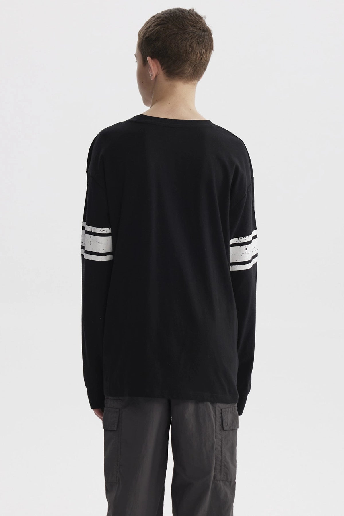 Polera negra de niño con franjas blancas en mangas y estampa colorida de texto 'Never Look Back' en el pecho