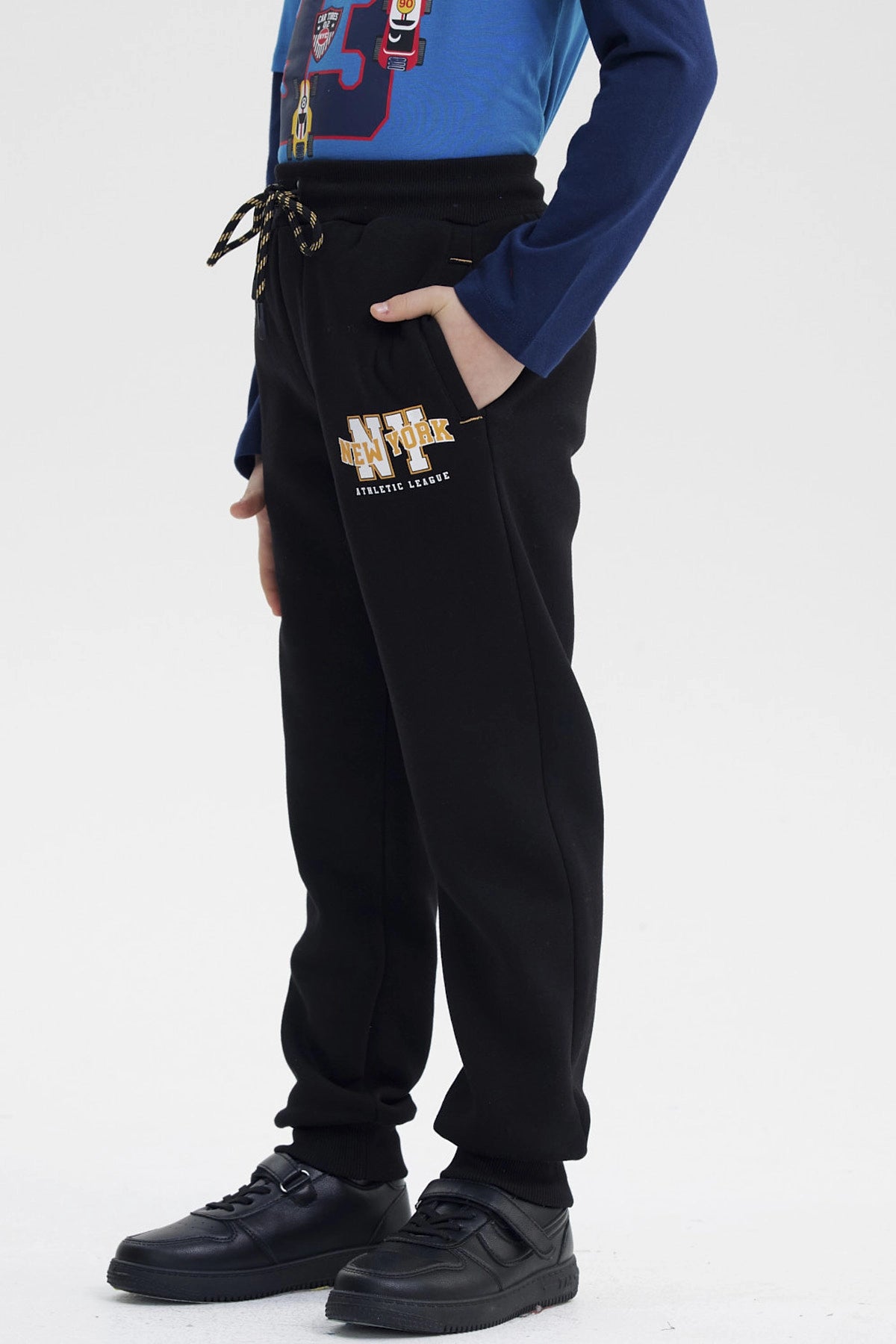 Pantalón jogger negro para niño con cordones en la cintura y pequeño logo "NEW ATHLETIC" en el muslo izquierdo