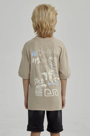 Polera de niño kaki con diseño gráfico abstracto en el pecho estilo urbano y mangas cortas ideal para días de juego