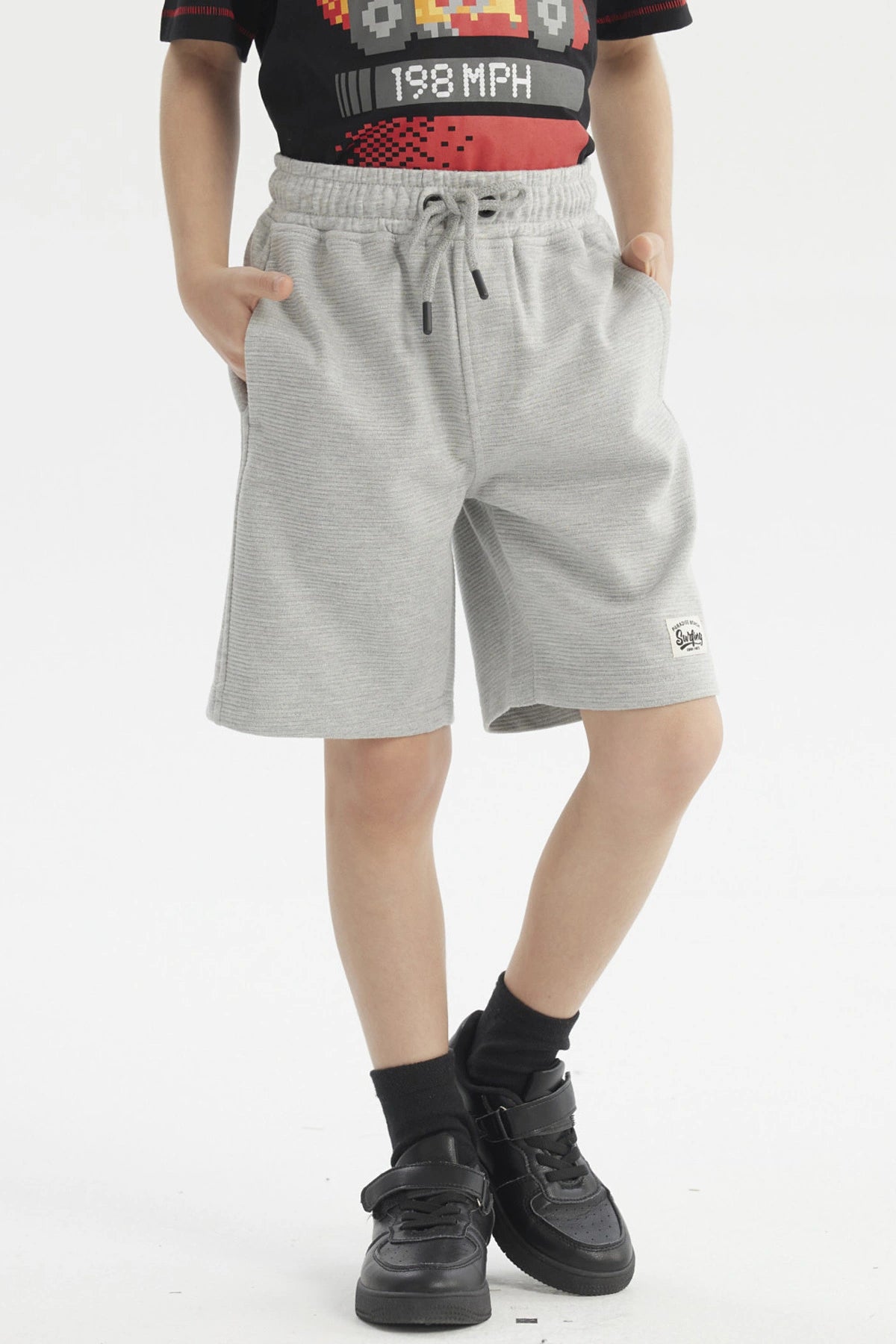 Bermuda niño gris melange con textura visible corte recto bolsillos laterales y pequeña etiqueta en el bajo izquierdo lisa