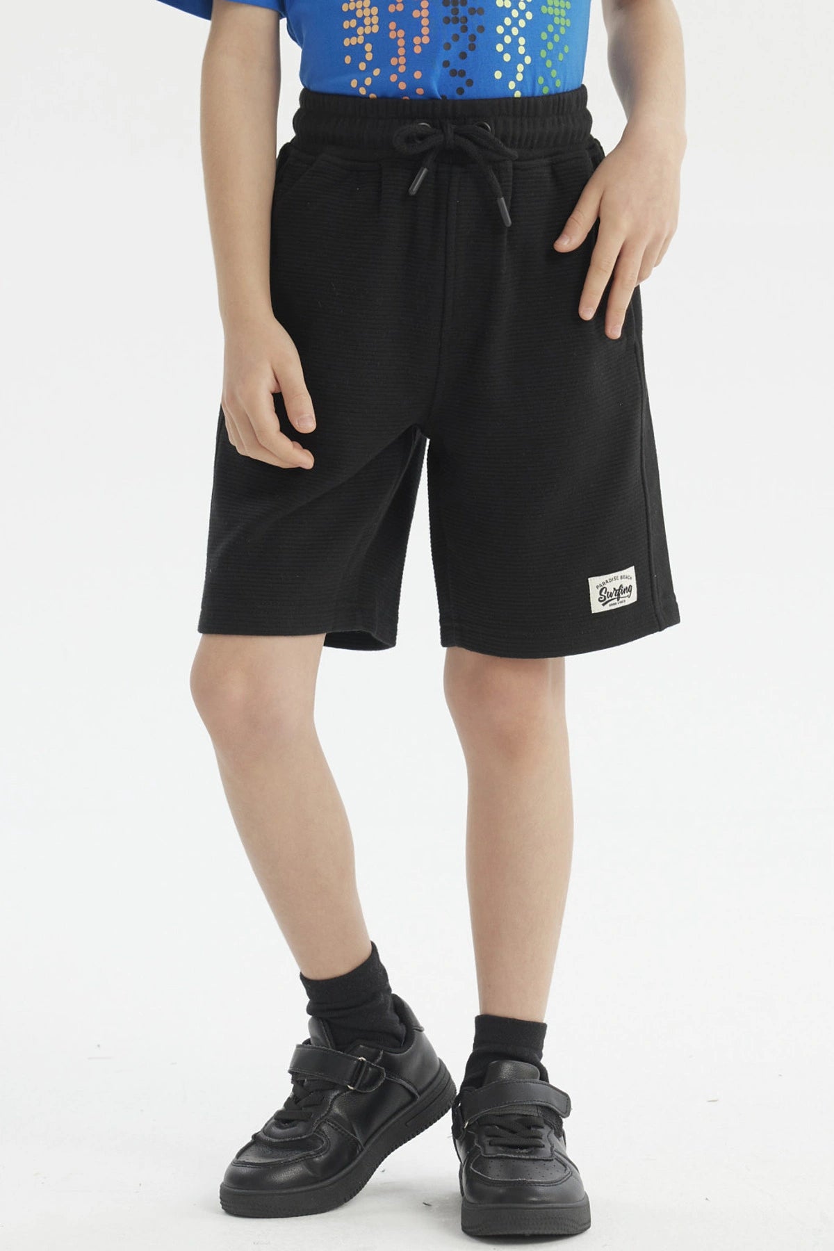Bermuda negra de niño con textura y etiqueta blanca pequeña en la pierna izquierda sin estampa lisa y cómoda