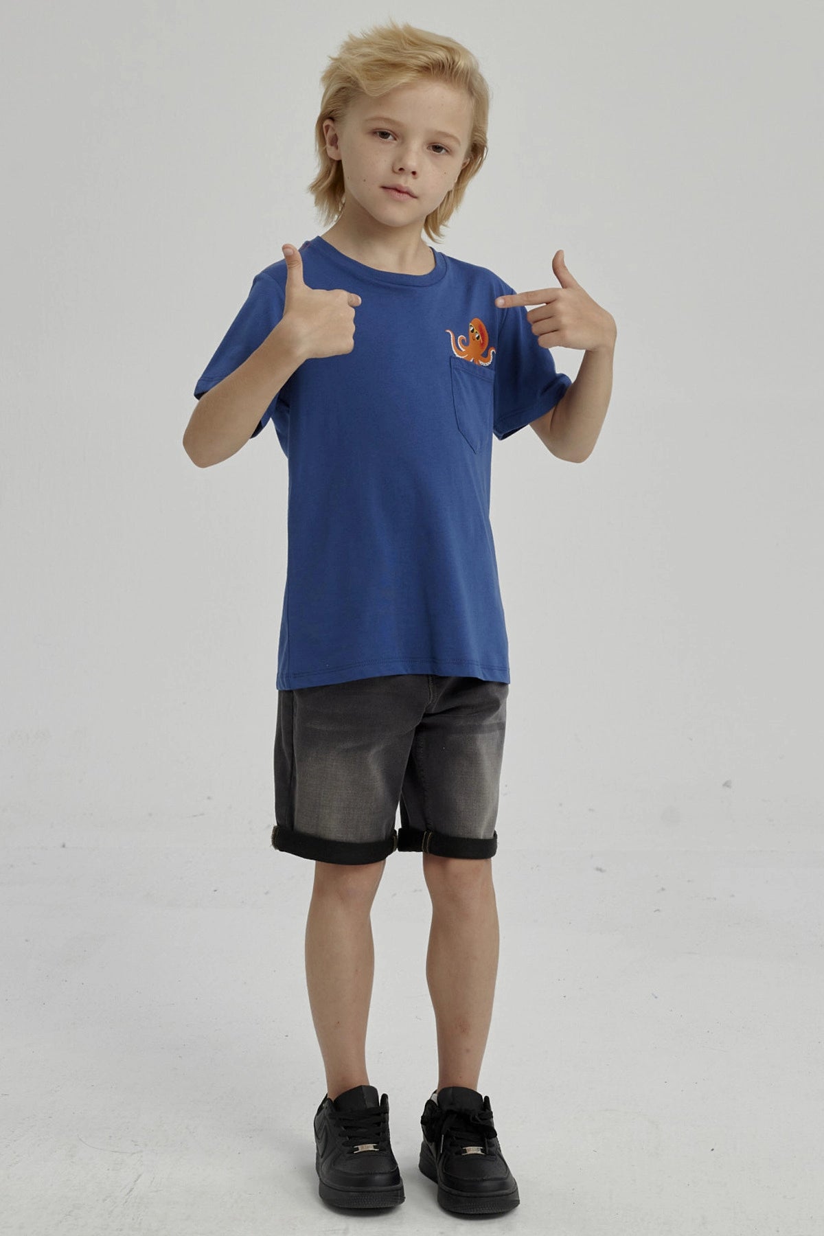 Polera azul para niño con bolsillo y estampado de pulpo naranja en el pecho pequeño y estilo caricatura