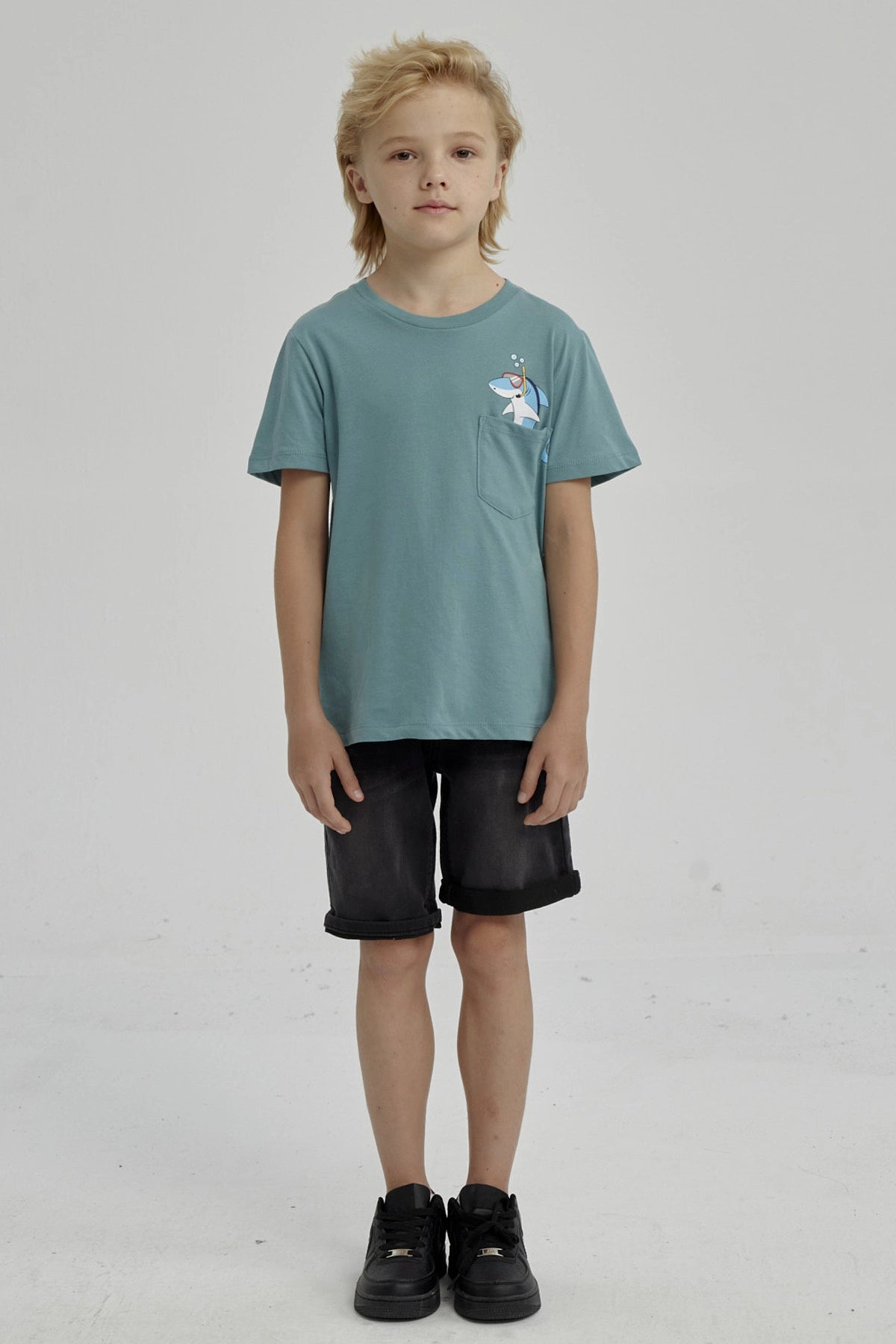 Polera verde para niño con bolsillo y estampado de tiburón con snorkel en el pecho estilo dibujo animado
