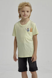 Polera amarilla para niño con bolsillo y estampa de esqueleto surfeando en estilo gráfico pequeño sobre el pecho