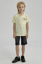 Polera amarilla para niño con bolsillo y estampa de esqueleto surfeando en estilo gráfico pequeño sobre el pecho