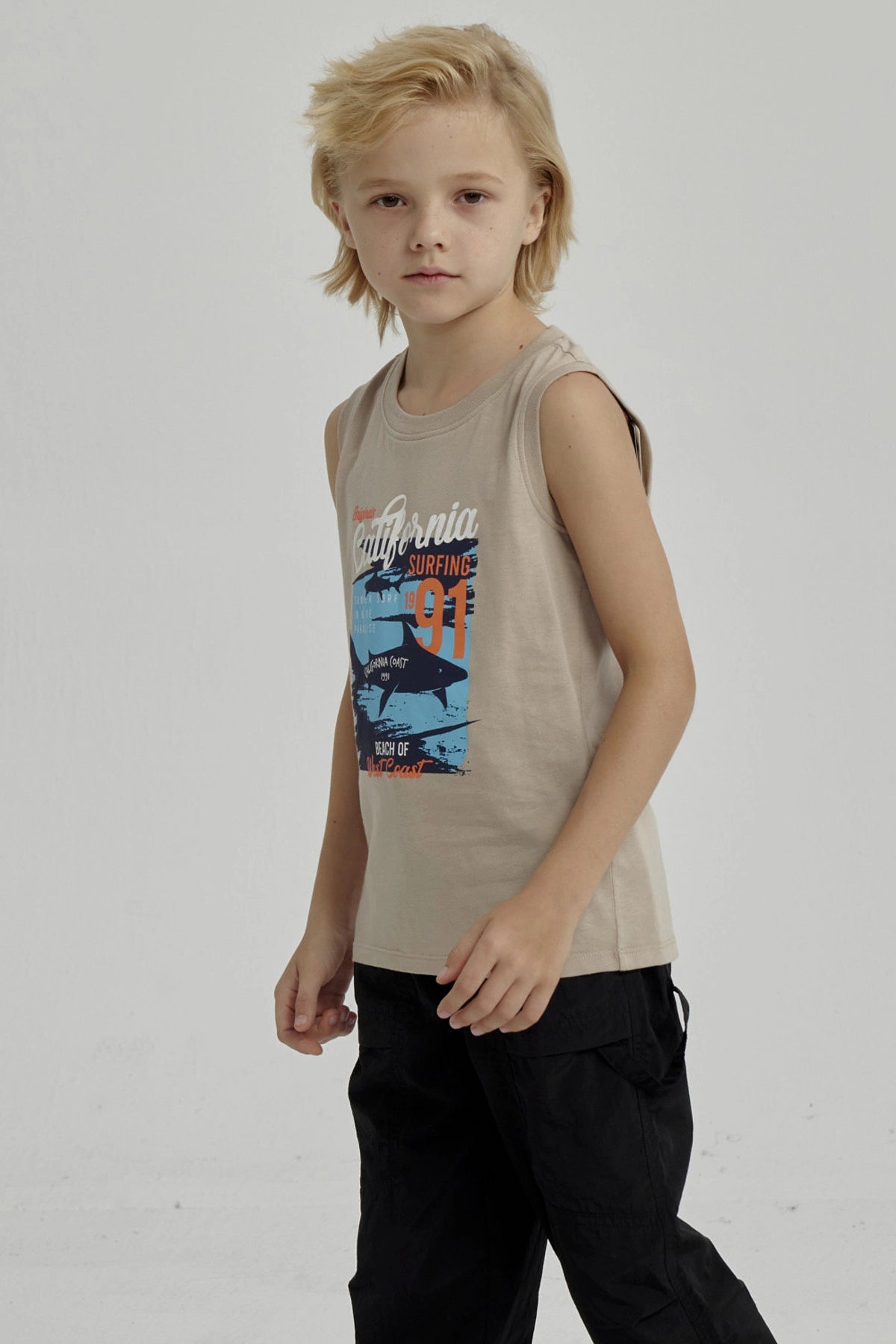 Polera sin mangas para niño color kaki con estampado grande de surf y tiburón en estilo gráfico playero California en el pecho