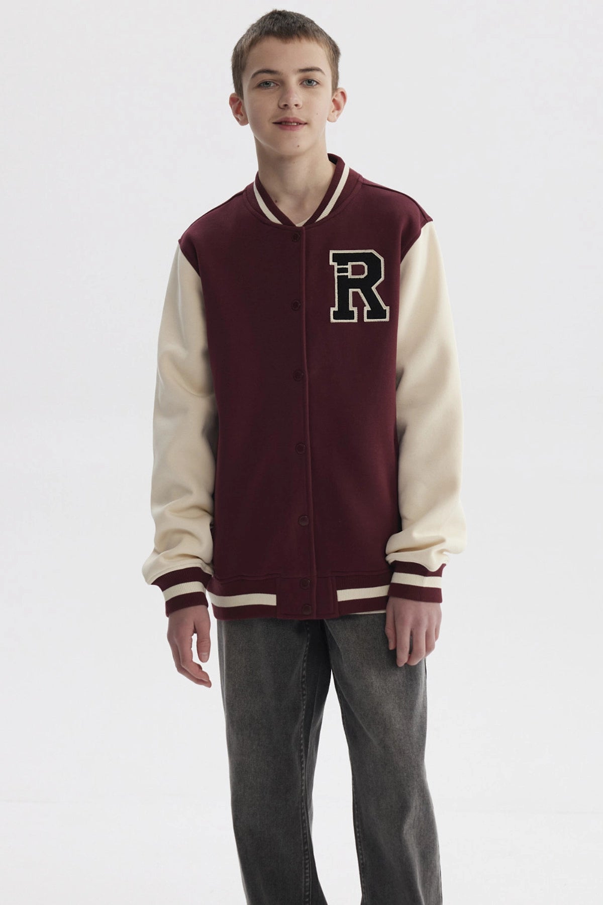Chaqueta tipo college burdeo para niño con mangas beige y gran letra R en el pecho estilo universitario
