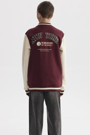 Chaqueta tipo college burdeo para niño con mangas beige y gran letra R en el pecho estilo universitario