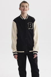 Chaqueta de niño estilo college en negro con mangas beige y letra B grande en el pecho estilo varsity
