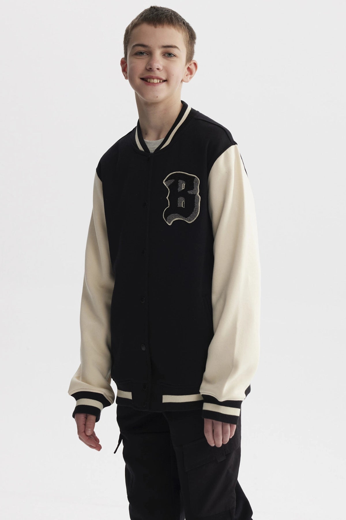 Chaqueta de niño estilo college en negro con mangas beige y letra B grande en el pecho estilo varsity