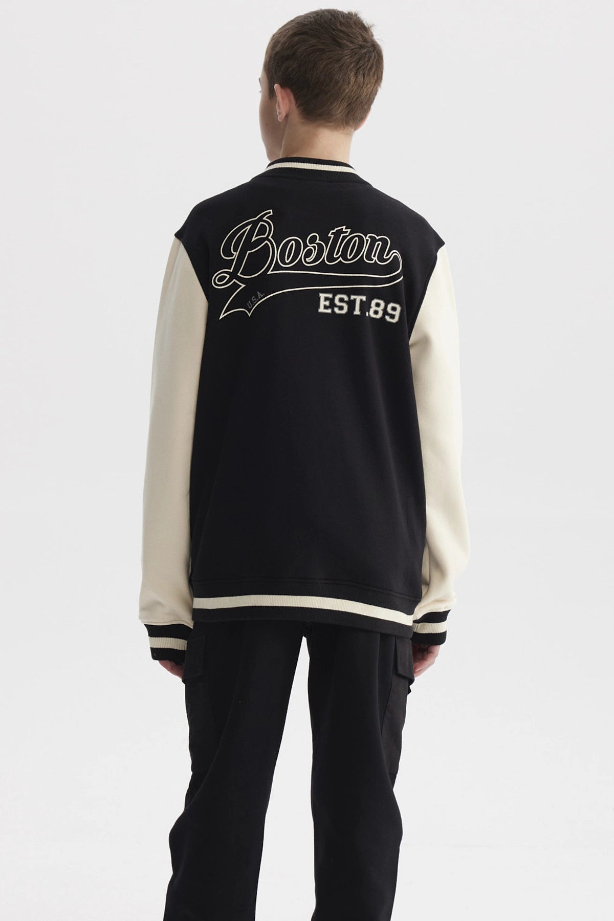 Chaqueta de niño estilo college en negro con mangas beige y letra B grande en el pecho estilo varsity