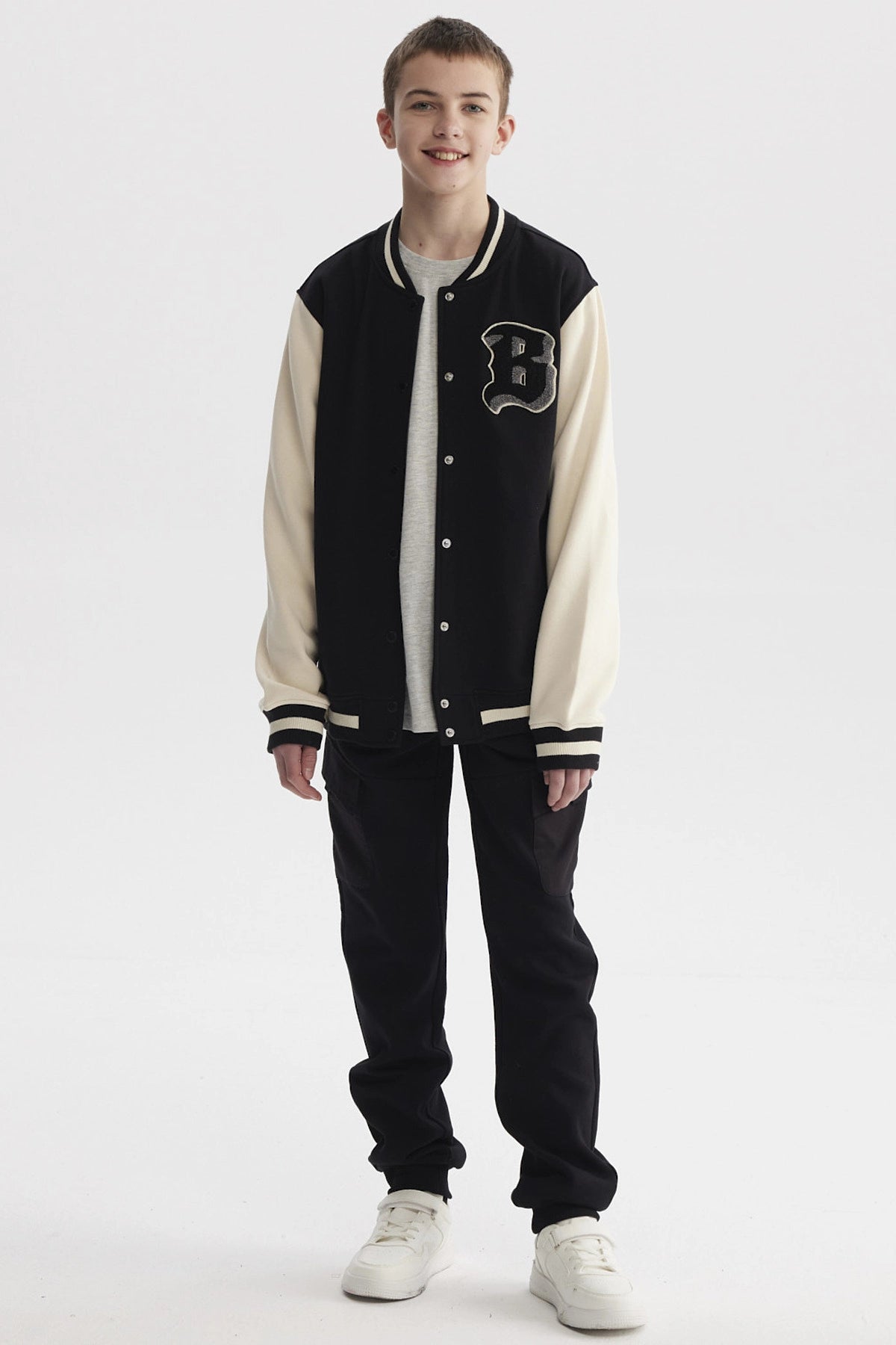 Chaqueta de niño estilo college en negro con mangas beige y letra B grande en el pecho estilo varsity
