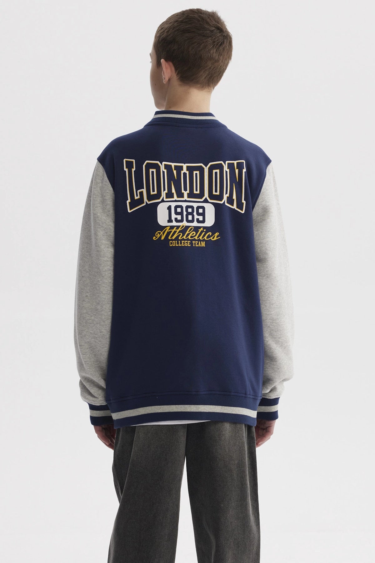 Chaqueta niño azul oscuro estilo college con mangas grises y estampado frontal pequeño de números en el pecho