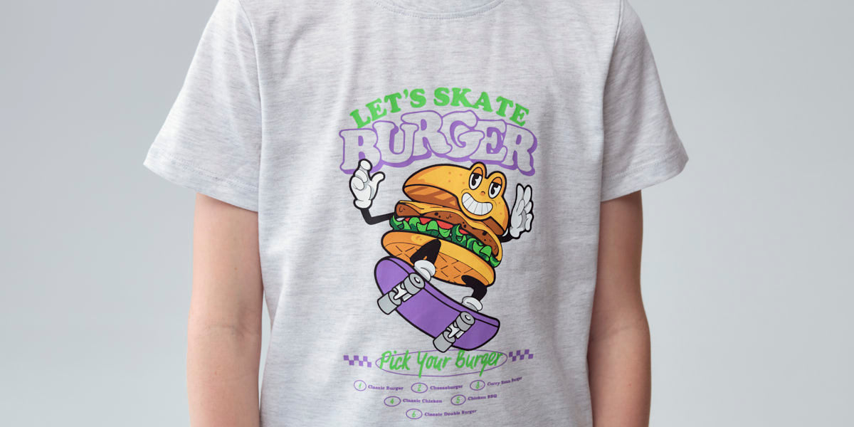 Polera gris melange claro para niño con estampado de hamburguesa sobre patineta