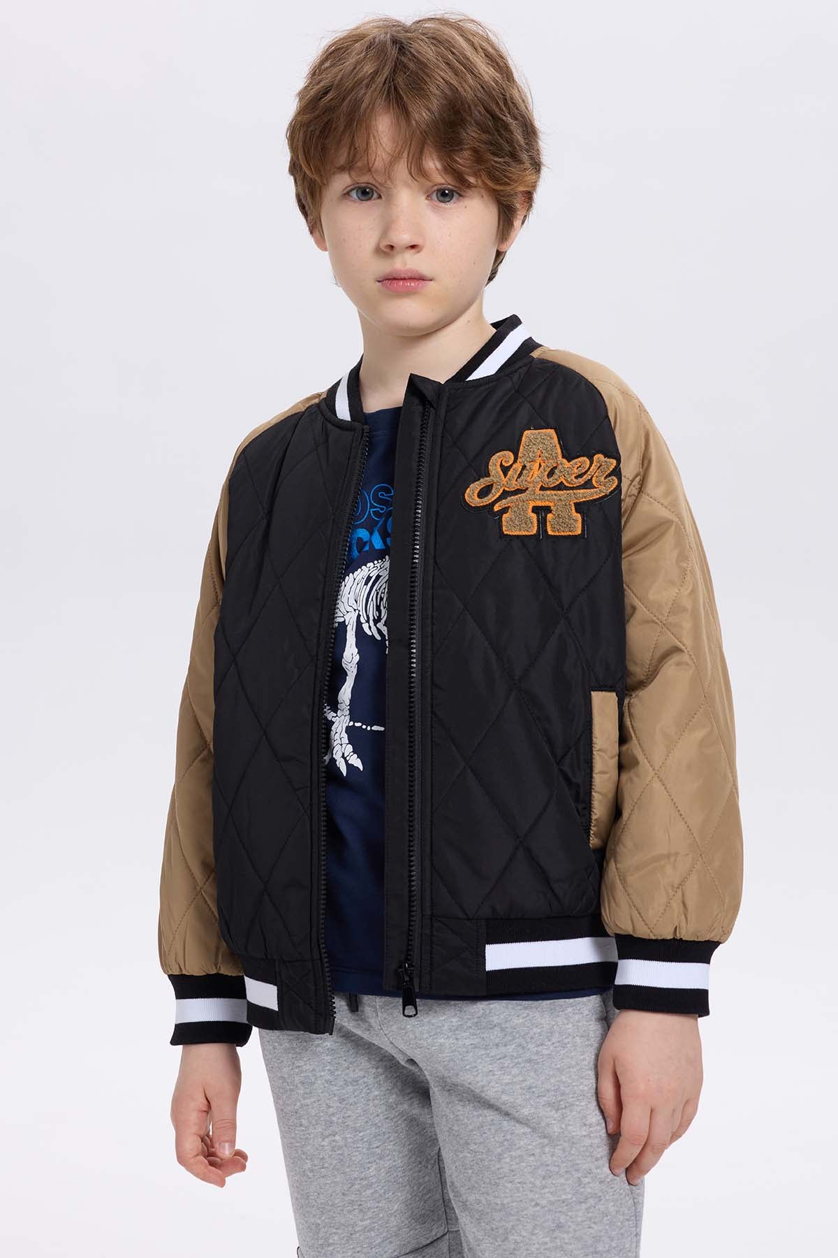 Chaqueta niño bomber negra con mangas beige y bordado