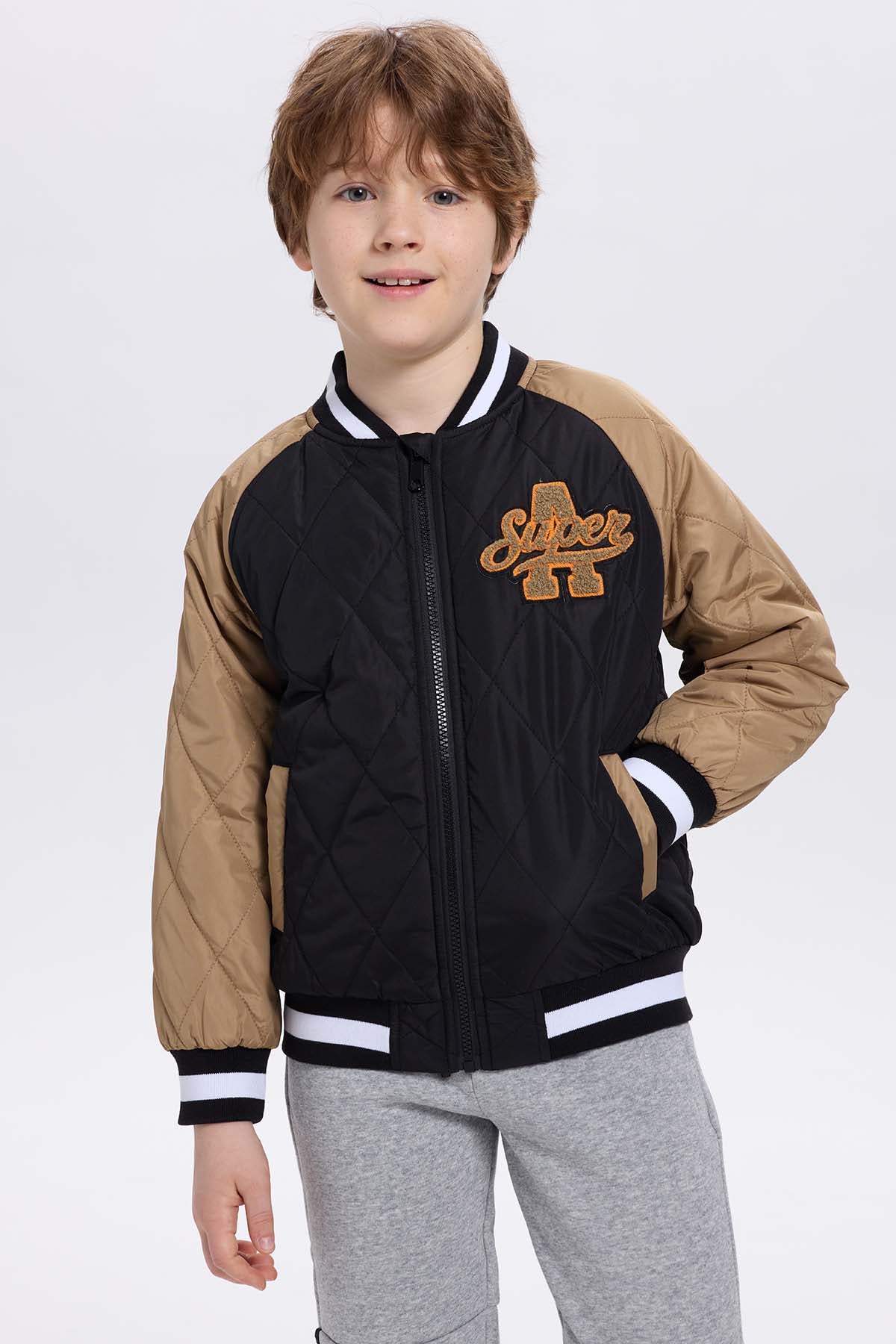 Chaqueta niño bomber negra con mangas beige y bordado