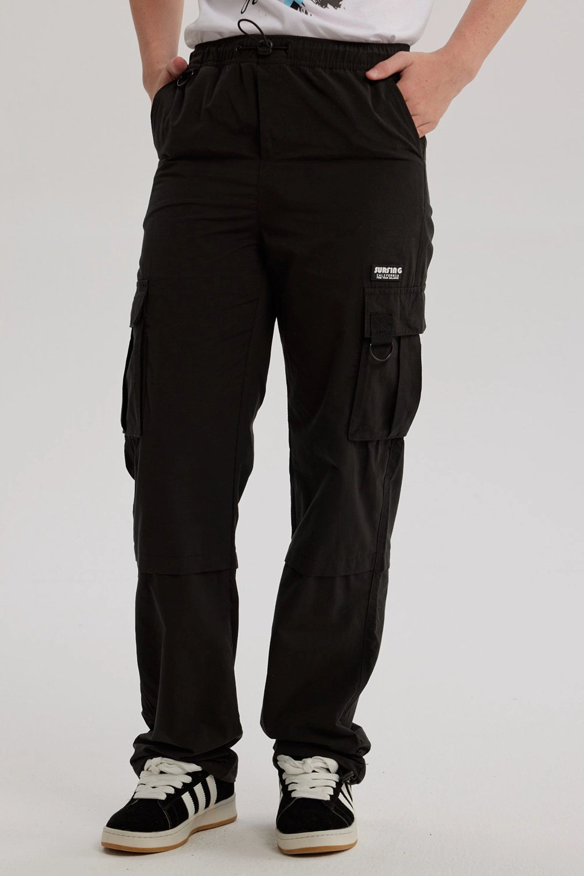 Pantalón niño negro calce recto cargo con bolsillos grandes laterales y detalle de etiqueta blanca sobre fondo negro