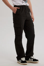 Pantalón niño negro calce recto cargo con bolsillos grandes laterales y detalle de etiqueta blanca sobre fondo negro
