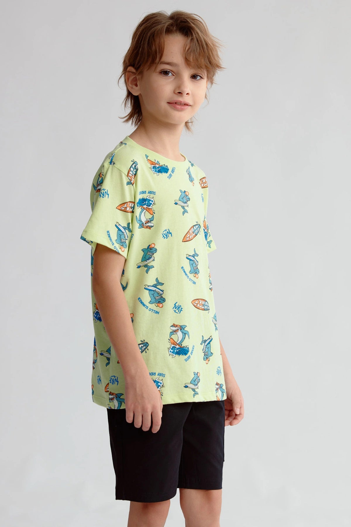 Polera niño verde claro con estampado de surfistas y tablas de surf