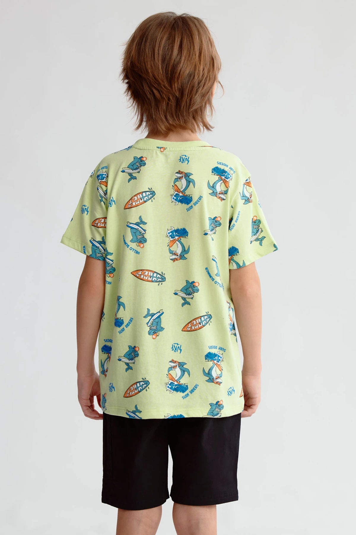 Polera niño verde claro con estampado de surfistas y tablas de surf