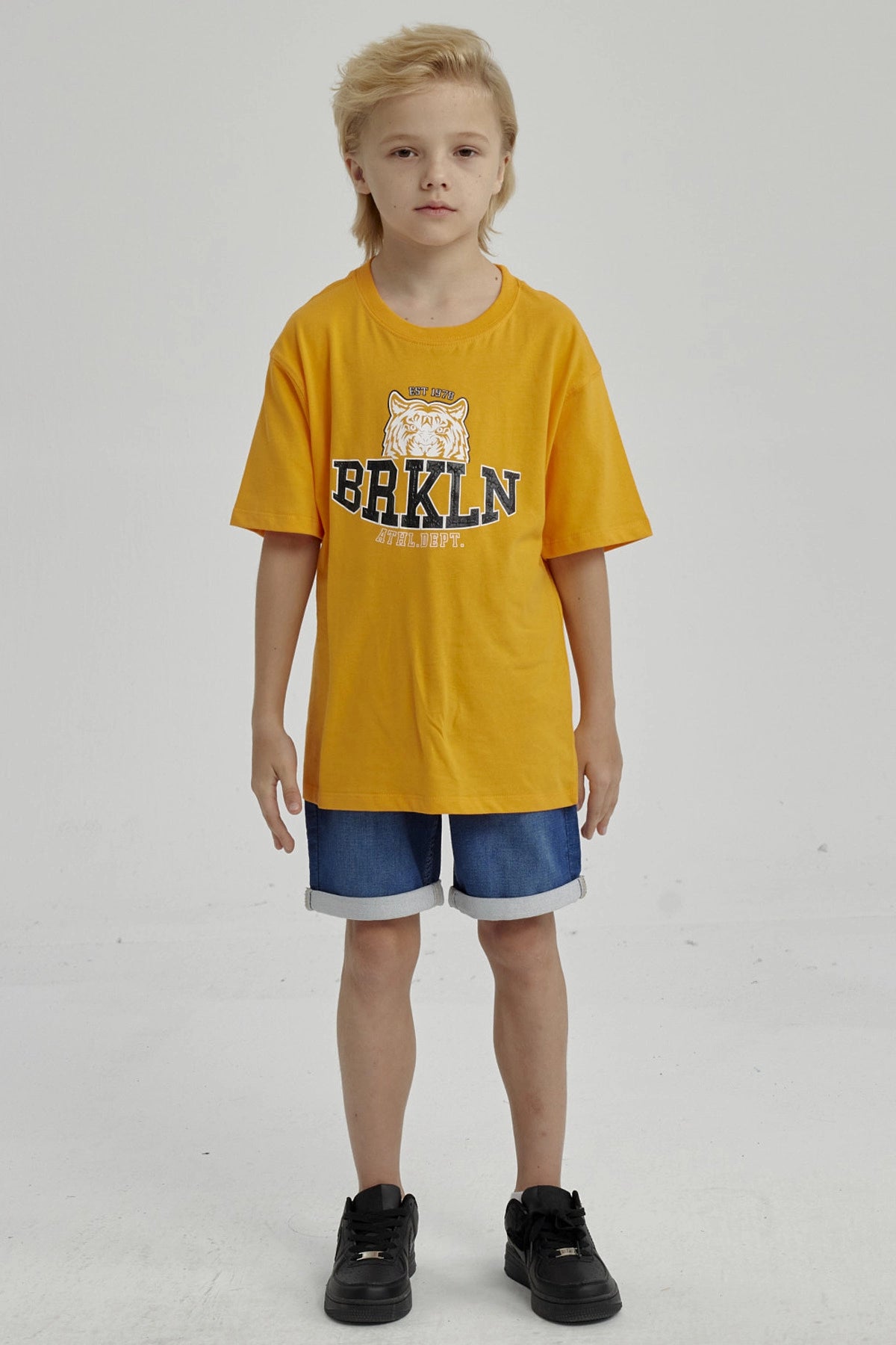 Polera naranjo de niño con estampa de tigre y texto BRKLN al frente en estilo deportivo casual