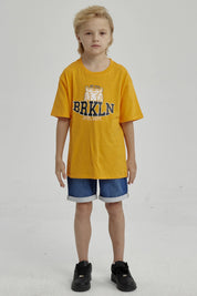 Polera naranjo de niño con estampa de tigre y texto BRKLN al frente en estilo deportivo casual