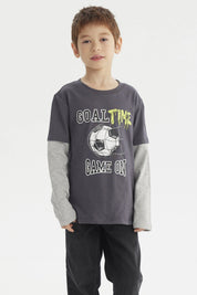 Polera de niño color marengo con estampado delantero de balón de fútbol y texto Goal Time Game On estilo deportivo casual