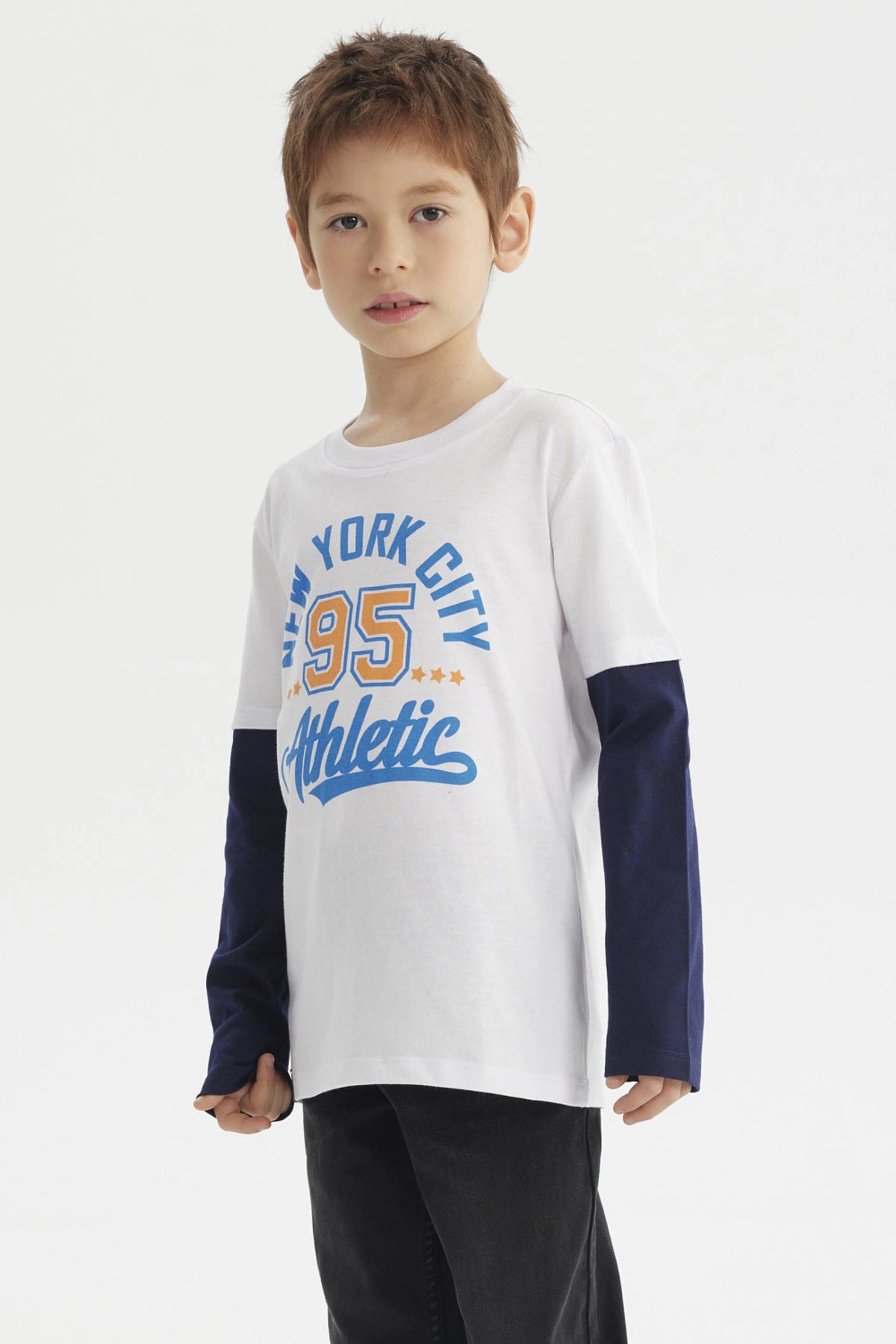 Polera blanca para niño con estampado grande New York City 95 Athletic en azul y amarillo al frente con mangas largas negras