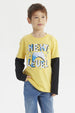 Polera amarilla de niño con estampa de control de videojuego azul y texto Next Level en el pecho