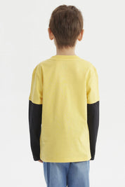 Polera amarilla para niño con mangas largas negras y estampado de control de videojuego y texto Next Level en el frente