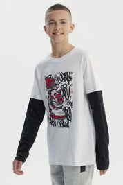 Polera niño blanca con mangas largas negras y estampa de zapatilla roja y negra en el centro con fondo de grafitis